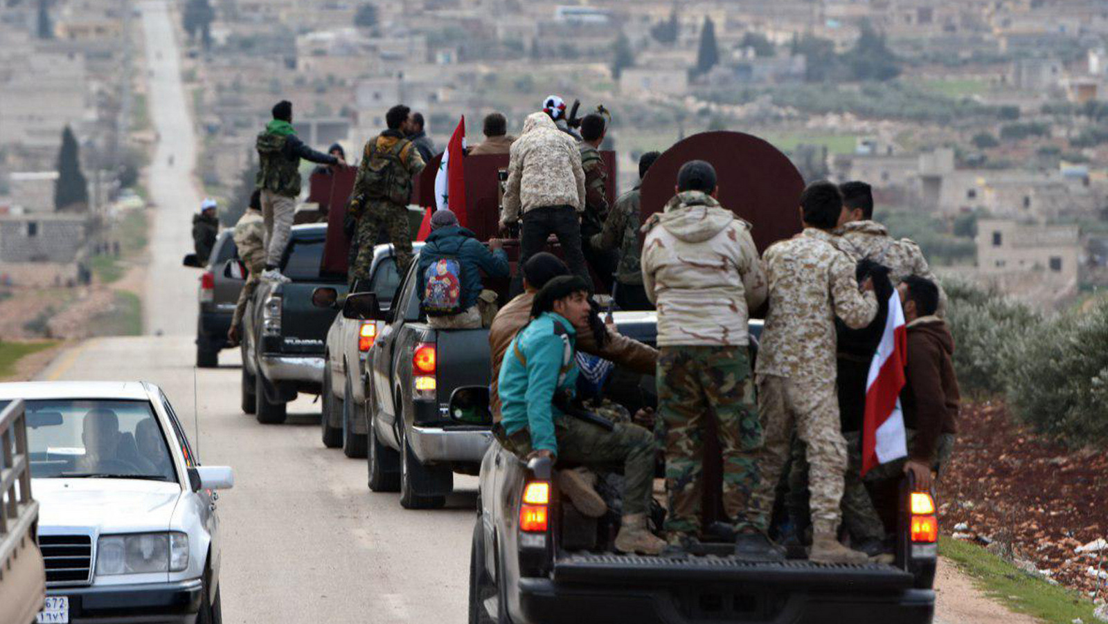 A convoy of militiamen loyal to the Syrian government on their way to aid the Kurds against Turkish forces, in the northern city of Afrin, Syria. (SANA via AP)