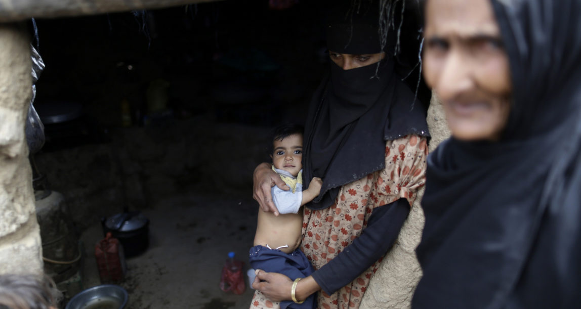 A displaced woman, center, holds her son at her family's hut at a camp for internally displaced people in the outskirts of Sanaa, Yemen, May 27, 2016. (AP/Hani Mohammed)