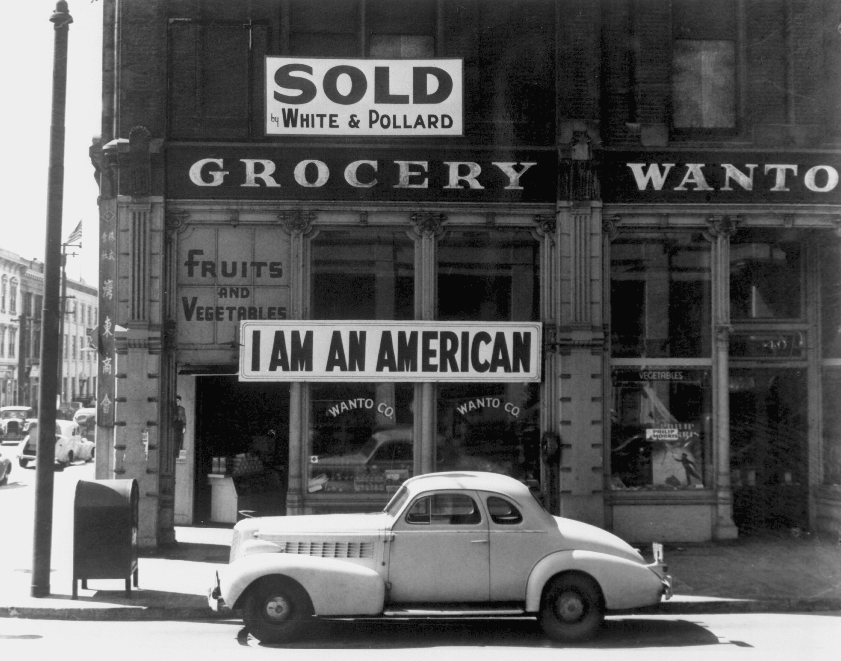 Following evacuation orders, this store was closed. The owner, a University of California graduate of Japanese descent, placed the "I AM AN AMERICAN" sign on the store front the day after Pearl Harbor. Oakland, CA, April 1942. Dorothea Lange.