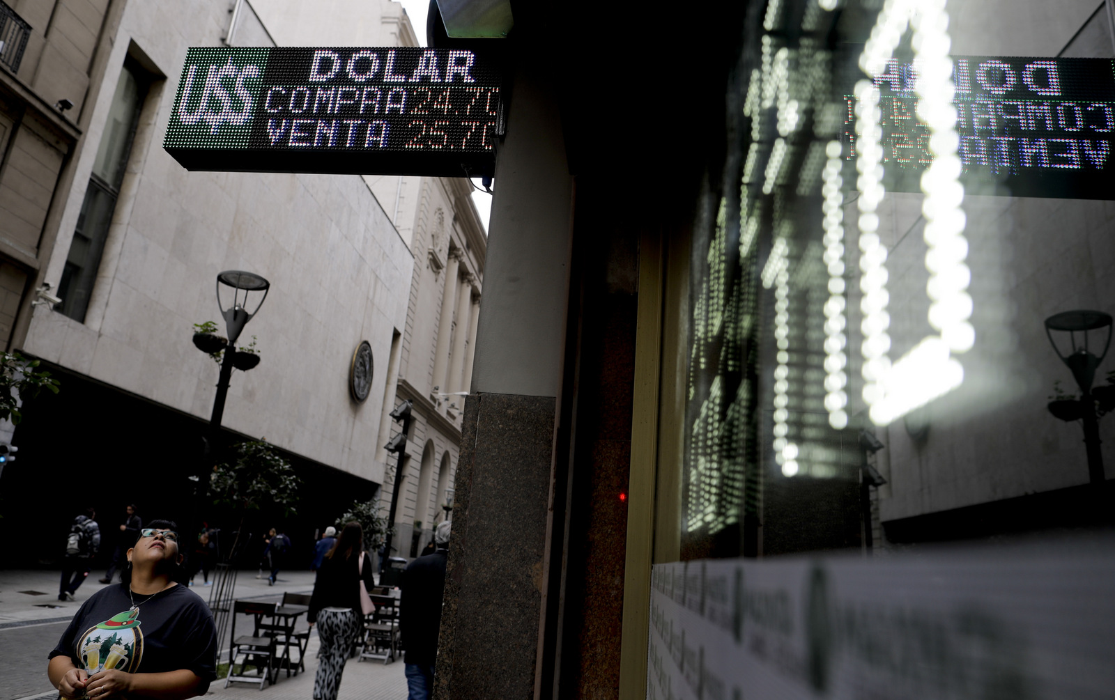 A woman looks up at a board showing the exchange rates between the Argentine peso and the U.S. dollar, in Buenos Aires, Argentina, May 15, 2018. Natacha Pisarenko | AP