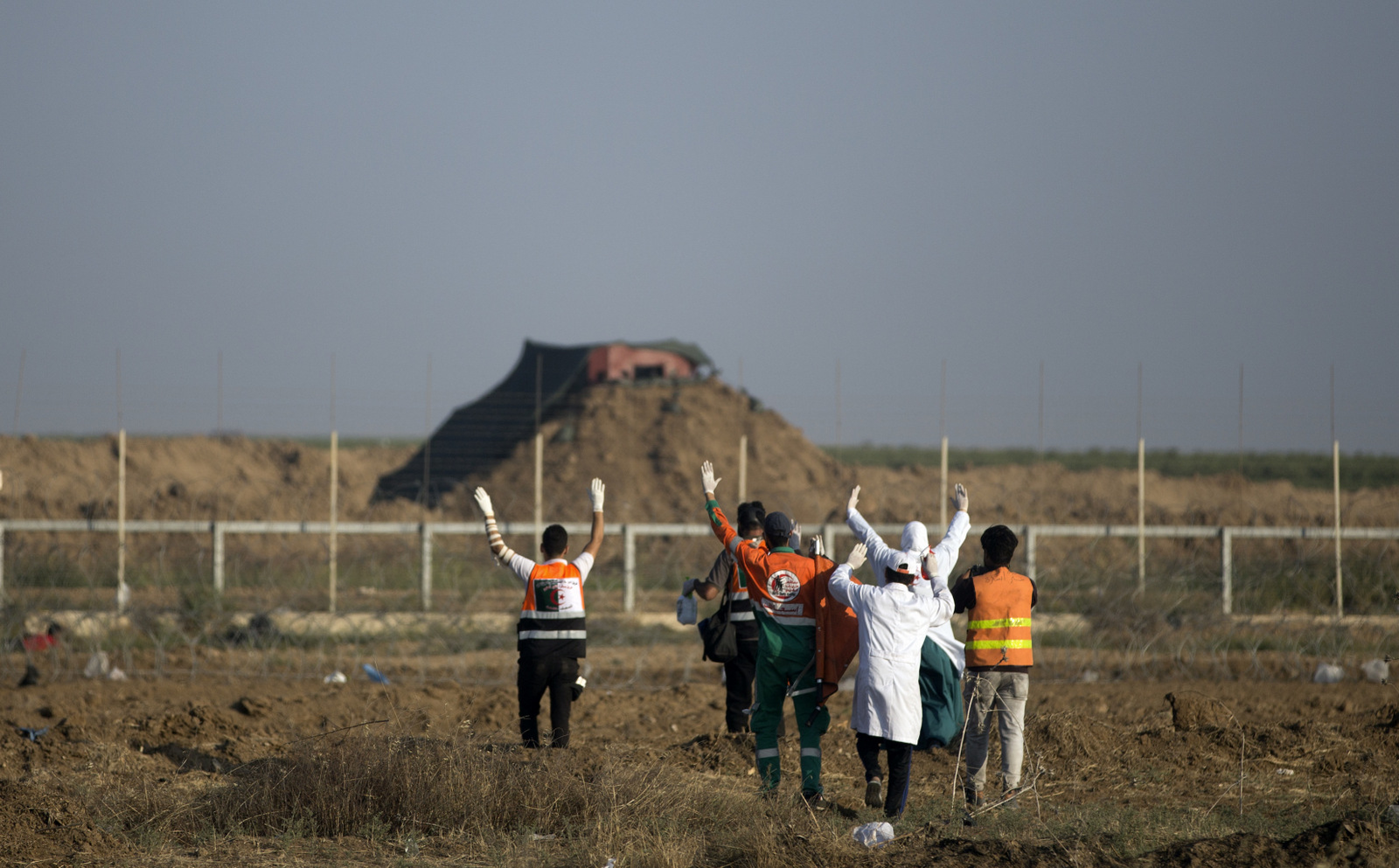 Palestinian medics raise their hands while walking towards an Israeli sniper nest near the border with Israel to evacuate injured protesters, May 15, 2018 (AP/Khalil Hamra)