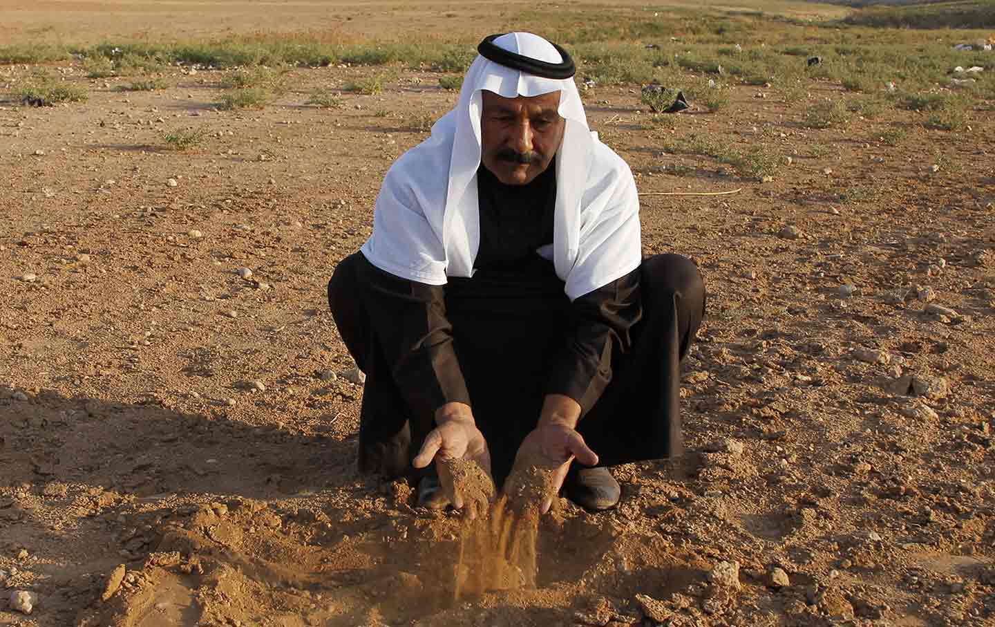 Sheikh Ghazi Rashad Hrimis handles dried earth in the parched region of Raqqa province in eastern Syria, during the drought that displaced half a million people, November 11, 2010. (Reuters/Khaled al-Hariri)