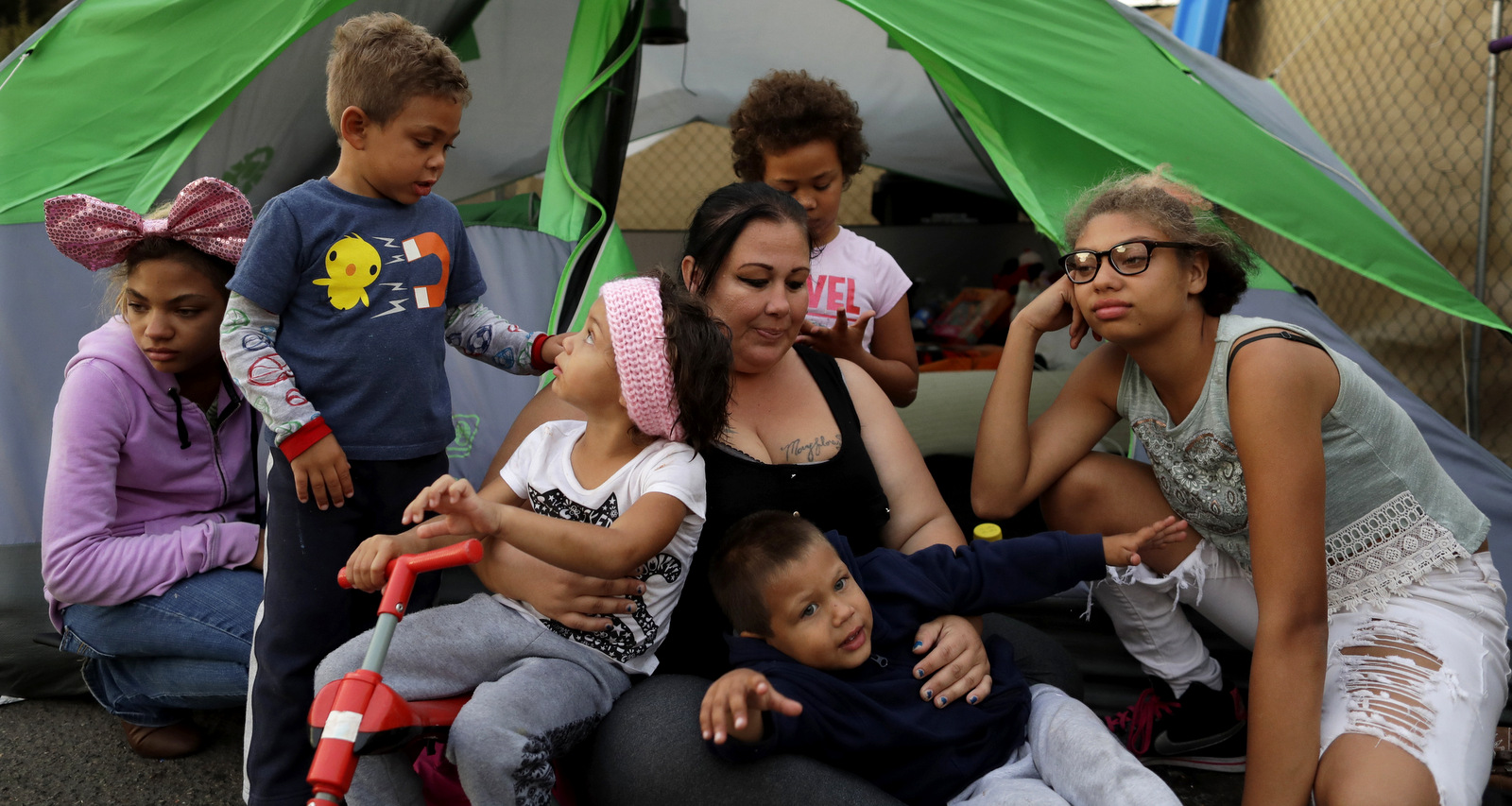 Christine Wade sits among her children in front of their donated tent in the city-sanctioned encampment on a parking lot in San Diego. They are, from left, Shawnni, 12, Roland, 4, Rayahna, 3, Jaymason, 2, Brooklyn, 8, and Shaccoya, 14. The Wade family is among several hundred people living in the city's first campground open for the homeless, set up to curb the worst Hepatitis A outbreak in the United States in decades. Gregory Bull | AP