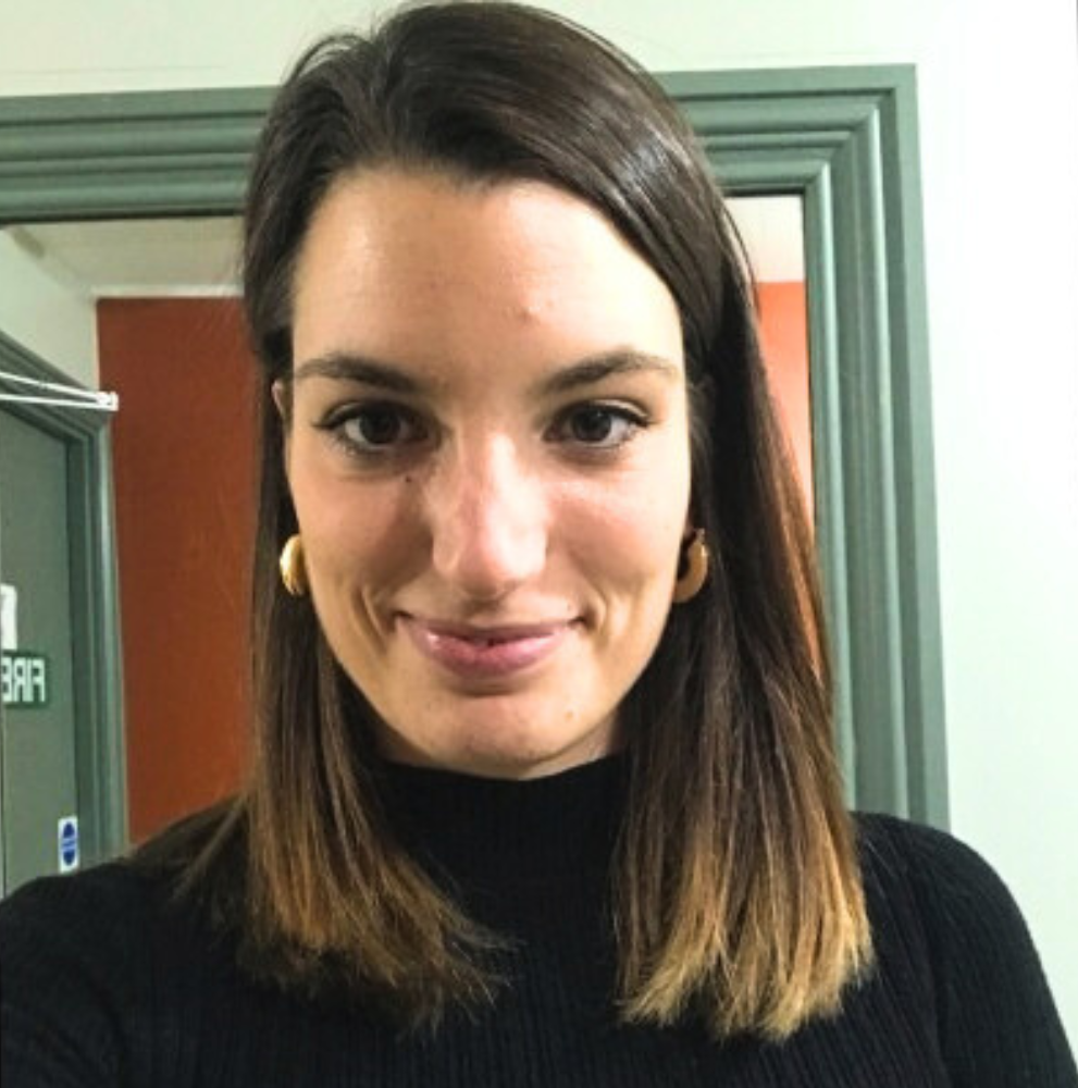 Portrait of Deborah Fiorin in a black top with gold hoop earrings, smiling